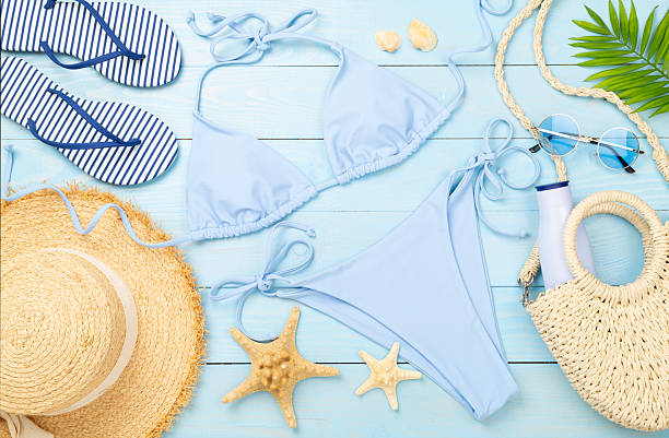 istock Blue bikini with beach accessories on wooden background, top view 2235009747