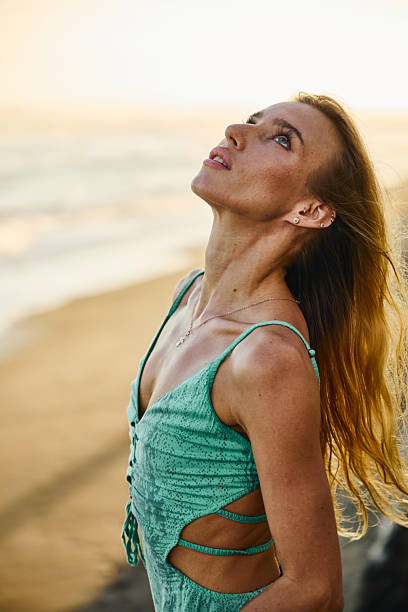 istock Young woman looking up while standing on the beach 2235010734