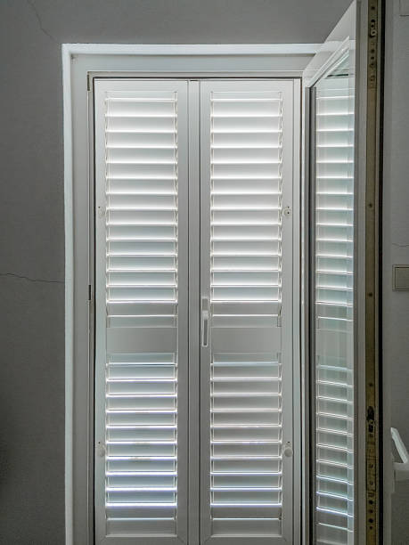 istock Interior view of closed white shutters with louvered panels softly filtering daylight, providing modern privacy, quiet, and geometric pattern to a peaceful home environment. 2235010790