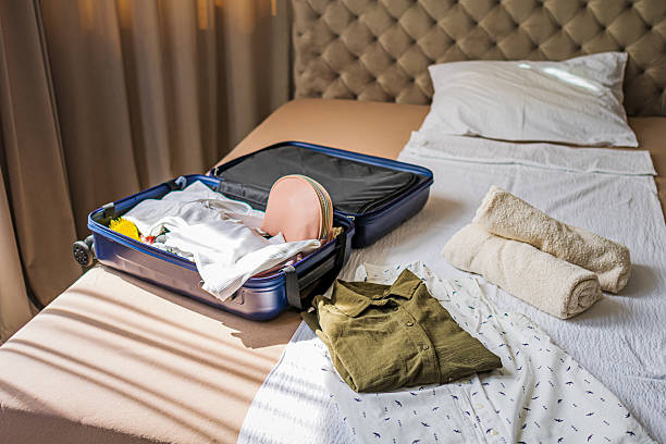 istock Opened blue suitcase with clothes and accessories  on bed in a modern hotel room, luxurious resort lodge. Ready for vacation, traveling, summer holiday, adventure. 2235011455