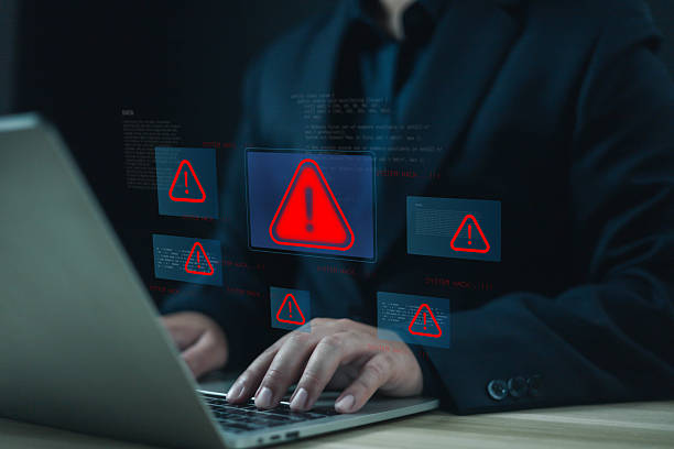 istock Businessman using laptop with red warning alert icons on screen, symbolizing cyber security threat, hacking, malware, and data breach risk in modern digital technology and online system. 2235011708