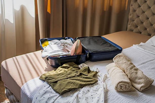 istock Opened blue suitcase with clothes and accessories  on bed in a modern hotel room, luxurious resort lodge. Ready for vacation, traveling, summer holiday, adventure. 2235011777