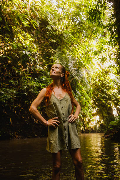 istock Young woman standing in a lush green forest with natural sunlight 2235012000