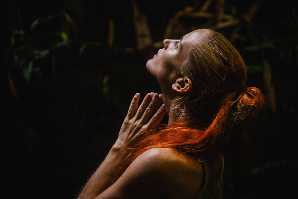 istock Reflective woman with clasped hands gazing upward in dim light 2235012022
