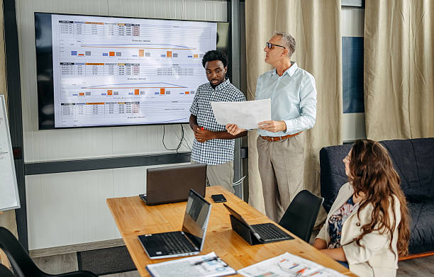 istock Small group of people having a business meeting using laptops while one person is presenting in front of projector screen 2235012604