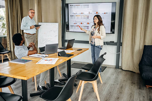 istock Small group of people having a business meeting using laptops and having discussion while standing in front of projector screen 2235012663