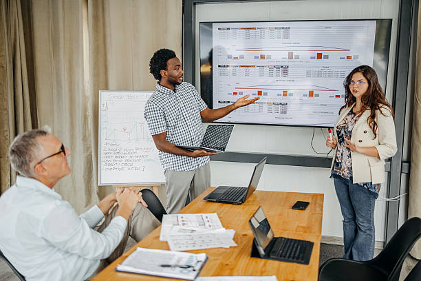 istock Small group of people having a business meeting using laptops and having discussion while standing in front of projector screen 2235012672