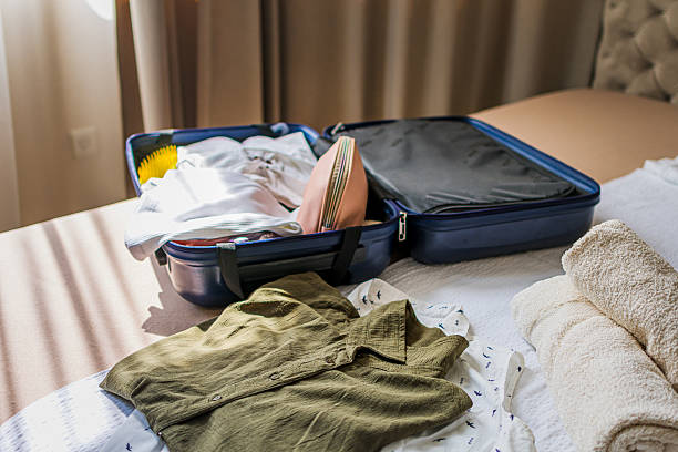 istock Opened blue suitcase with clothes and accessories  on bed in a modern hotel room, luxurious resort lodge. Ready for vacation, traveling, summer holiday, adventure. 2235012743