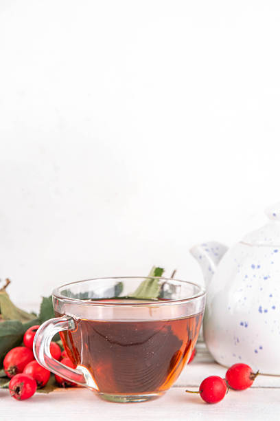 Fragrant autumn hawthorn berry tea. Herbal organic hot drink made from wild forest hawthorn berries, on white wooden background