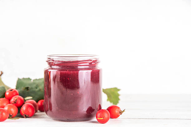 Wild forest hawthorn berry jam or marmalade in small jar with fresh berries on kitchen table, copy space