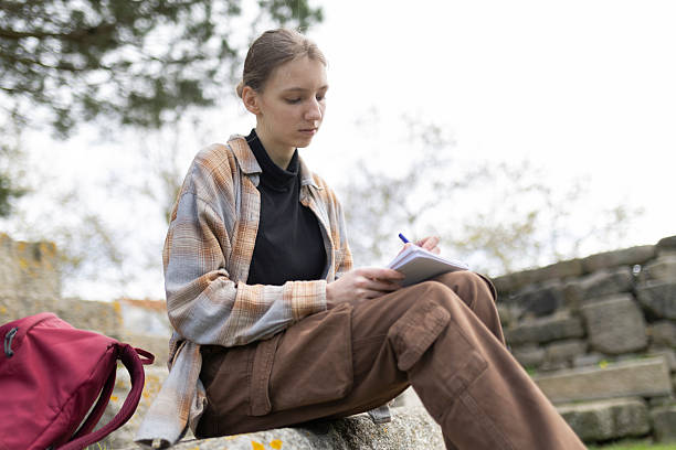 istock Young woman writing outdoors in archaeological site 2235017282