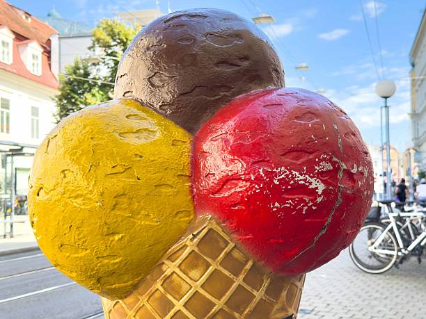 Large colorful ice cream cone sculpture in urban setting with trees