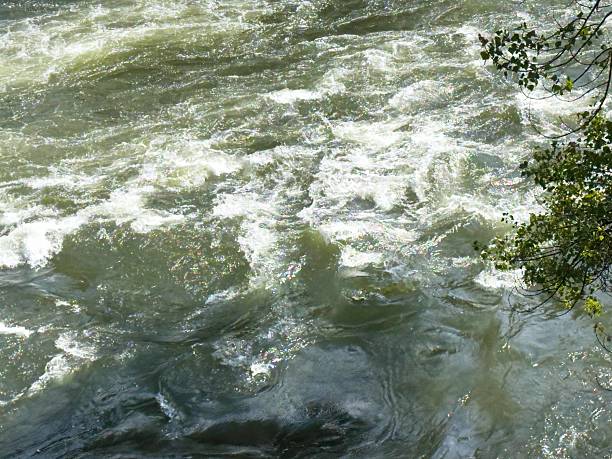 istock Rushing river water with ripples and sunlit reflections 2235017414