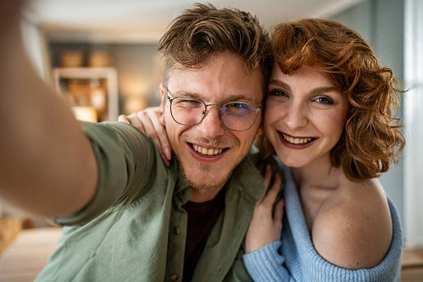 istock Cheerful young couple taking a selfie at home 2235018346