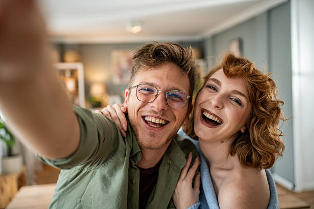 istock Cheerful young couple taking a selfie and having fun at home 2235018368