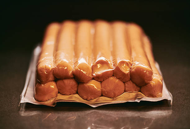 A tightly vacuum-sealed package of sausages neatly arranged in rows, preserving freshness and texture. Ideal for meal preparation or storage in a modern kitchen setting.
