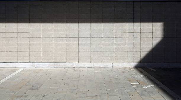 Rough concrete tile wall and dirty stone tile floor. Shadow in the upper and right side. Background for copy space.