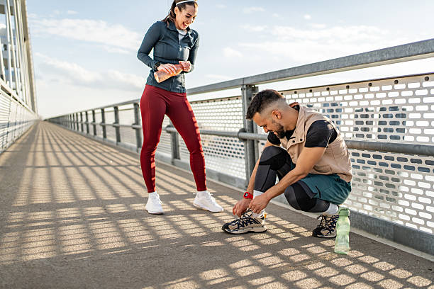 istock Runners tying shoelaces and drinking water on a bridge during a sunny day 2235022412