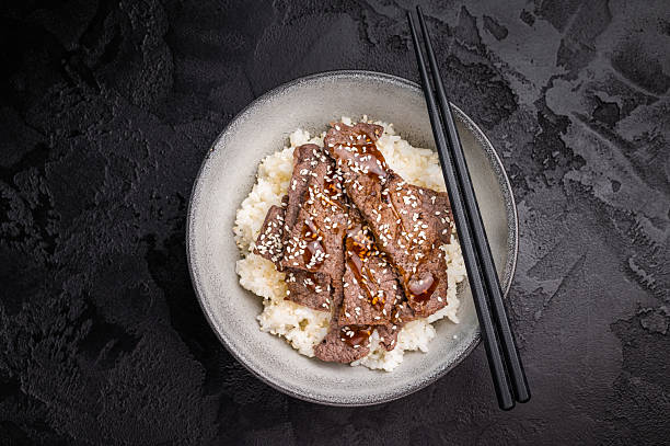 Yakiniku, wagyu marbled beef cuts and rice in a bowl. A culinary journey that captures the essence of Japanese grilling traditions. black background. top view