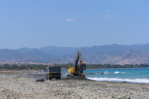 istock Excavator Loading Rocks and Sand into Dump Truck on Cyprus Beach 2235026018