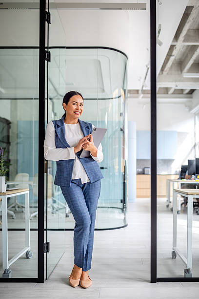 istock Professional Asian woman smiling in modern office environment while holding a tablet 2235027310