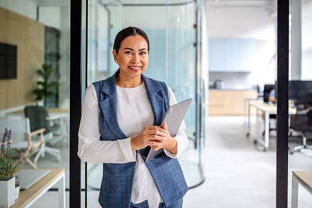 istock Professional Asian woman smiling confidently in a modern office environment while holding a tablet 2235027322