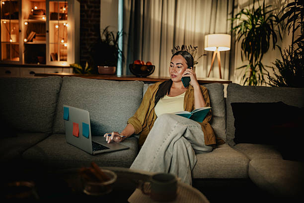 istock Mature woman engages in evening leisure activities at home while on a phone call and using a laptop 2235029120