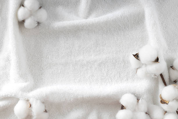 istock White terry towel texture decorated with cotton flower bud. Cosmetics background, spa frame backdrop. Bathroom items display.Empty copy space. 2235031976