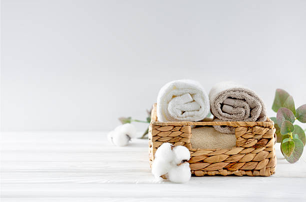 istock Rolled towels in straw basket decorated with cotton flowers on empty space table. Bathroom hygiene,spa background, product display. 2235031981