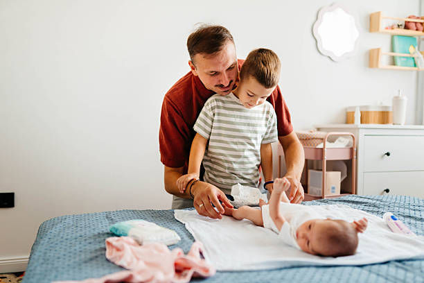 istock Dad and son changing a newborn baby's diaper 2235032309