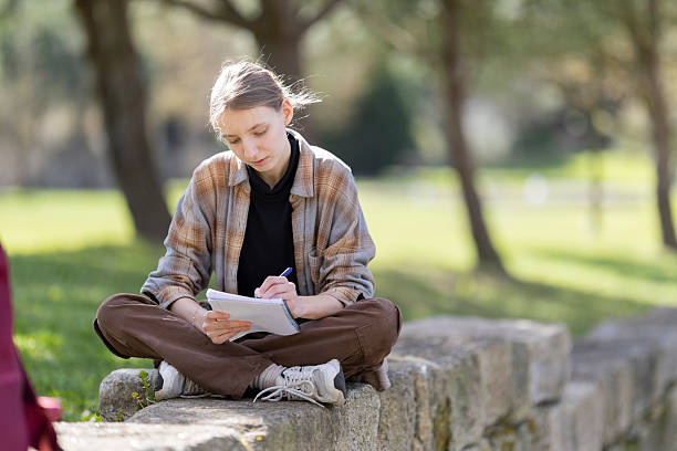 istock Young student writing outdoors in a park on a sunny day 2235034698