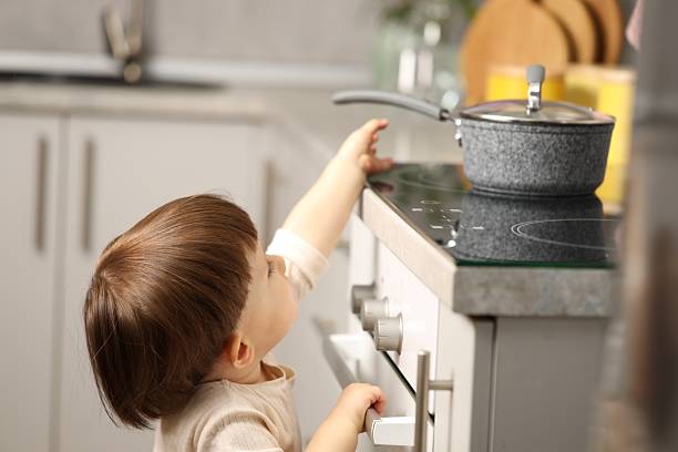 istock Little boy playing with pot on stove in kitchen. Dangerous situation 2235034879