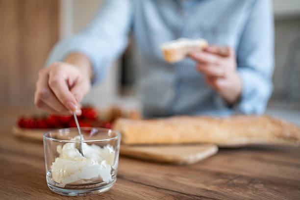 Close-up of a chef preparing a delicious baguette with cream cheese and cherry tomatoes in a modern kitchen, adding a touch of culinary expertise to the simple breakfast