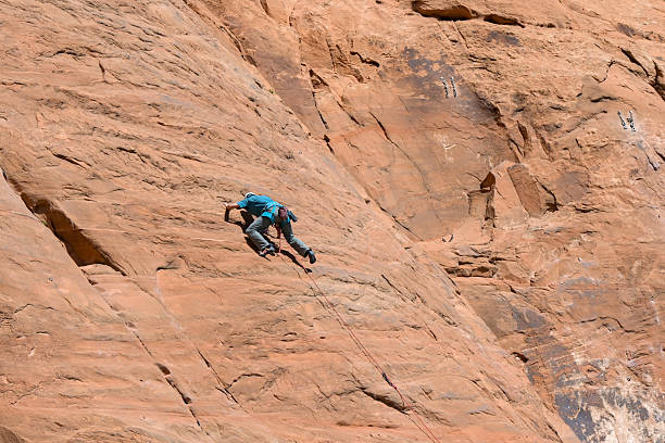 Moab, Utah, USA - 25 May 2025: Person climbing a sheer rock face using ropes on the outskirts of Moab