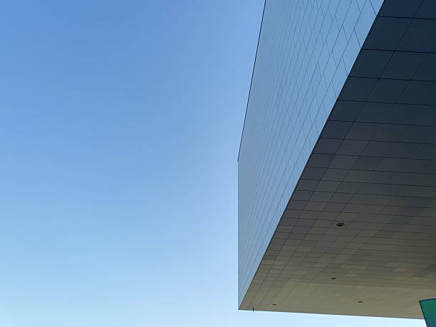 istock Modern glass building with rectangular structure on the right and clear blue sky on the left. Horizontal minimal urban architecture with copy space. Contemporary office facade. 2235037135