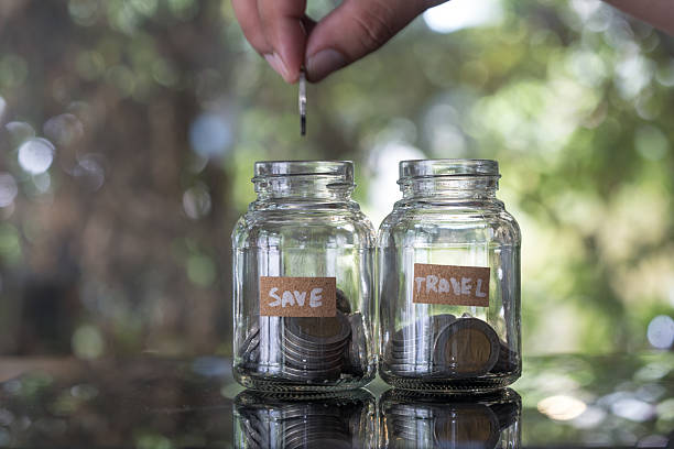 istock Saving money concept. Hand putting coin into glass jar save 2235037787