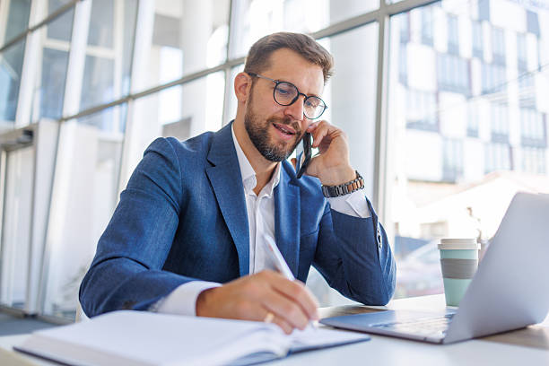 istock Businessman working on laptop and talking on phone in office 2235038076