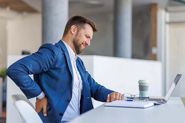 istock Businessman suffering from back pain while working on laptop in office 2235038282
