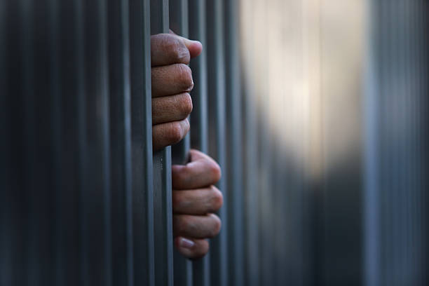 istock Hands Grasping Bars of Jail Cell Symbolizing Confinement and Despair 2235039125
