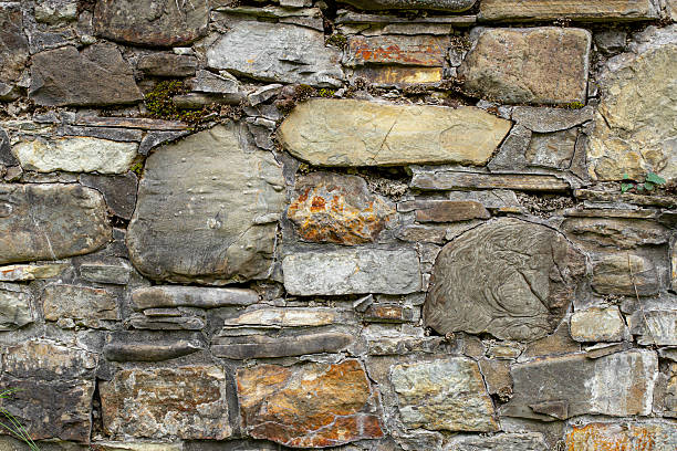istock Ancient weathered stone wall with plants and moss, abstract backdrop 2235041956