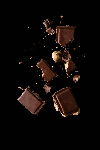 istock Broken milk chocolate with hazelnuts crumpled on black background 2235042387