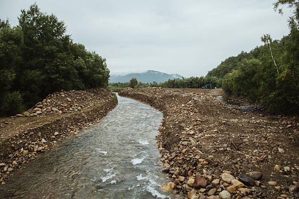 A man-made gravel riverbed in a mountainous area with alluvial banks