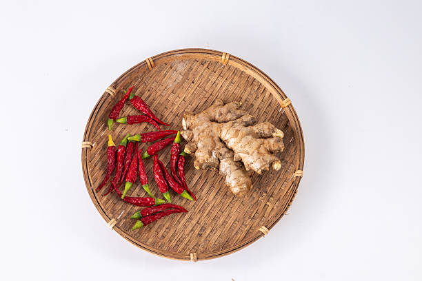 A group of white-backgrounded ginger and chili peppers shot in a studio.