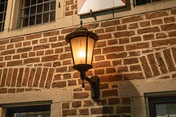 Vintage street lamp casting warm light on a textured brick wall, creating a nostalgic and atmospheric scene