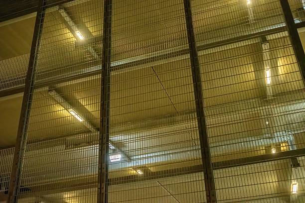 Layers of metal mesh grids protect the floors of a modern building, with lights shining through, creating an industrial and secure atmosphere
