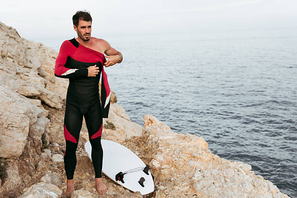 Smiling blonde man standing in the water with his blue surfboard