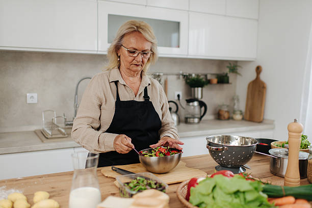 istock Senior woman preparing a fresh salad in a modern kitchen 2235050705
