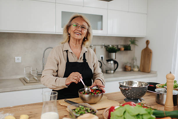 istock Senior woman preparing a fresh salad in a modern kitchen 2235050720