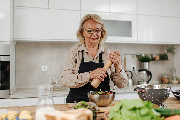 istock Senior woman seasoning fresh salad in modern kitchen 2235050737