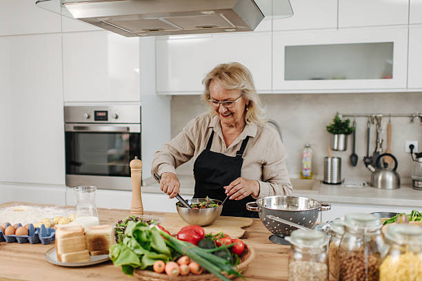 istock Senior woman mixing salad in modern kitchen 2235050759